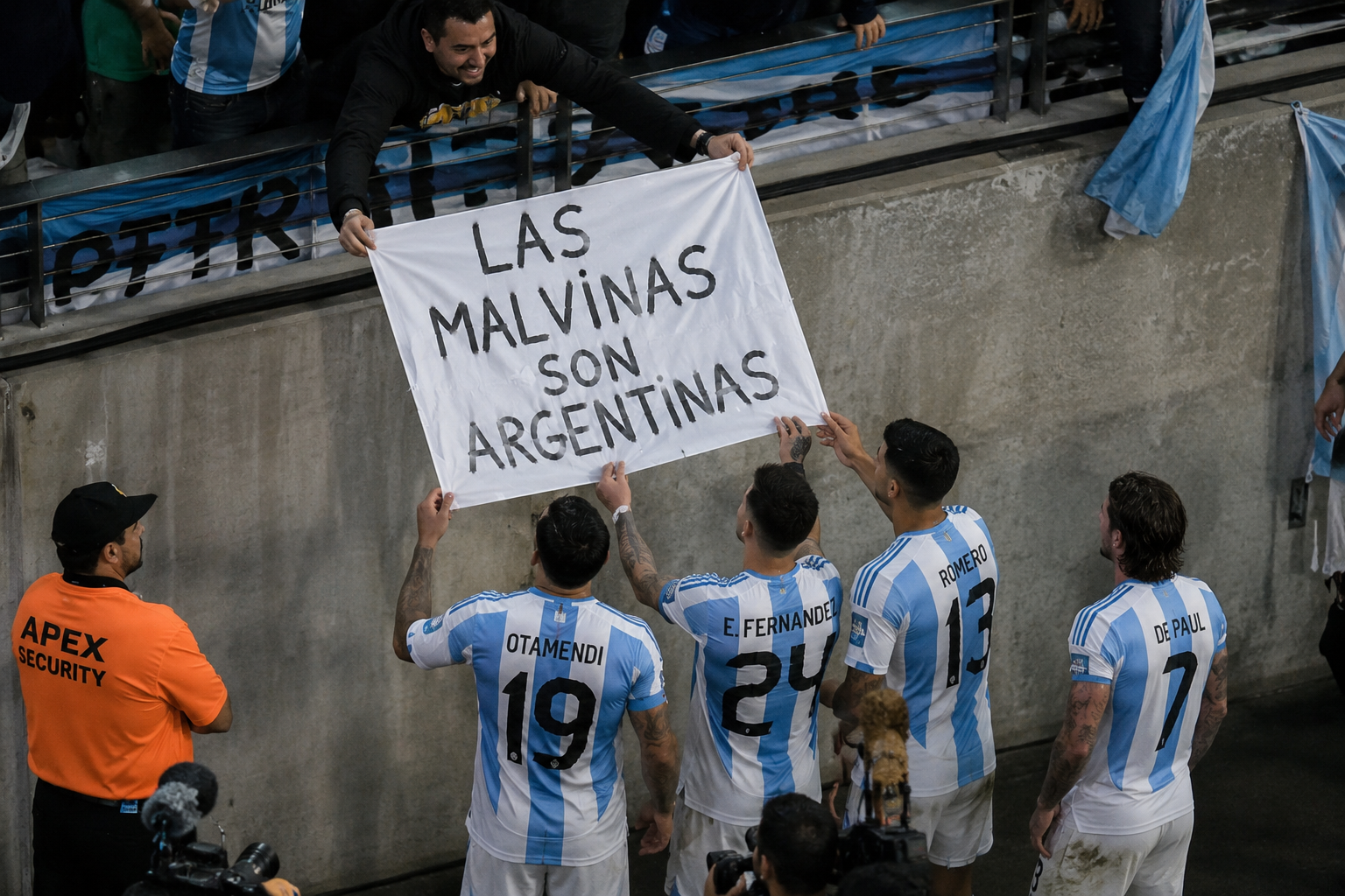 Argentine football players holding a banner reading “Las Malvinas son Argentinas” on the pitch.